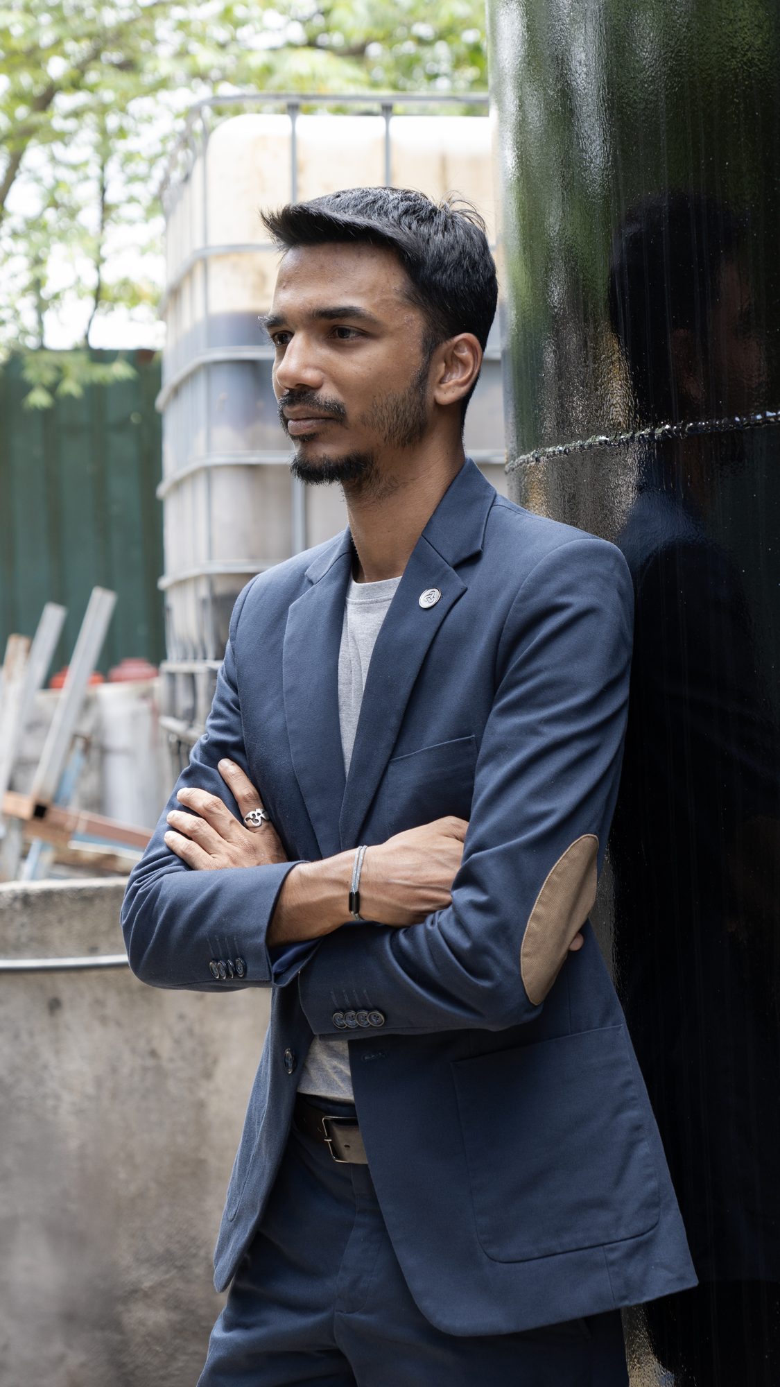 Vinesh Sinha, arms crossed, leaning on a black storage tank