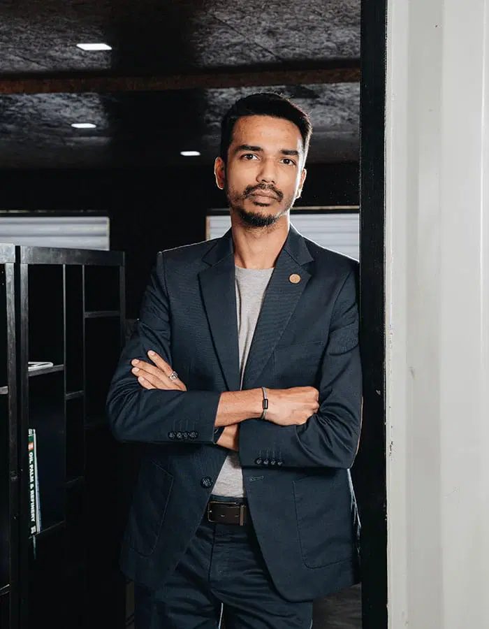 Vinesh Sinha, arms crossed, in a dark office